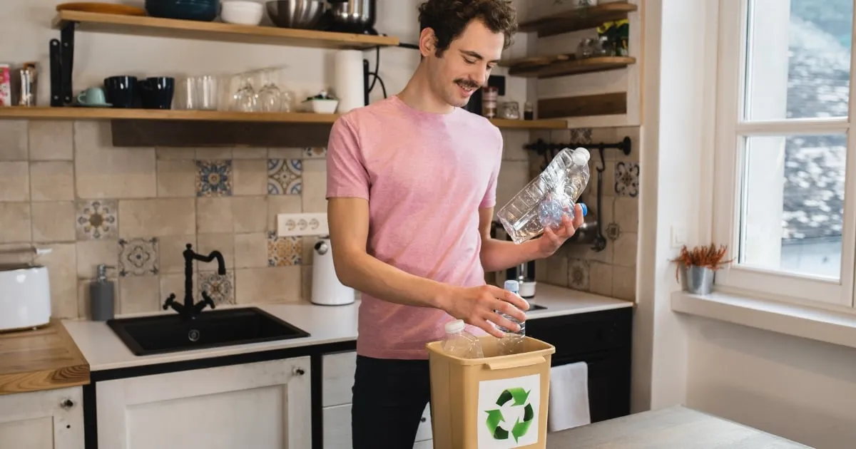 a man holding plastic bottles and putting it on the recyclable bin
