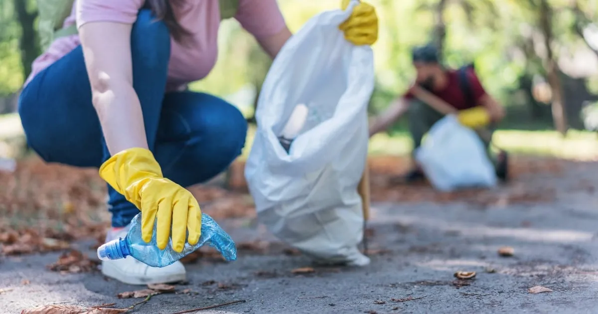 a woman wearing gloves and picking up trash