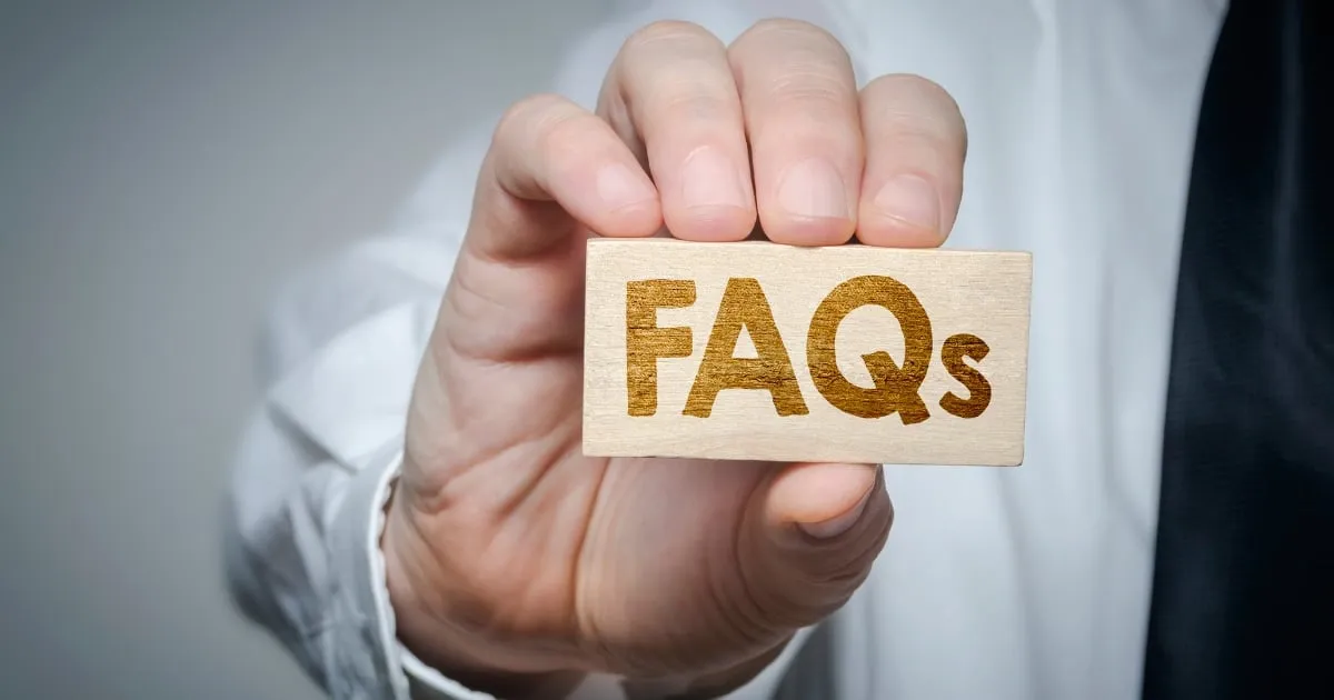 a hand holding a piece of wood with FAQs