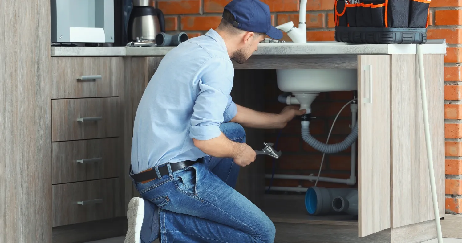 a professional plumber fixing the pipe under the sink