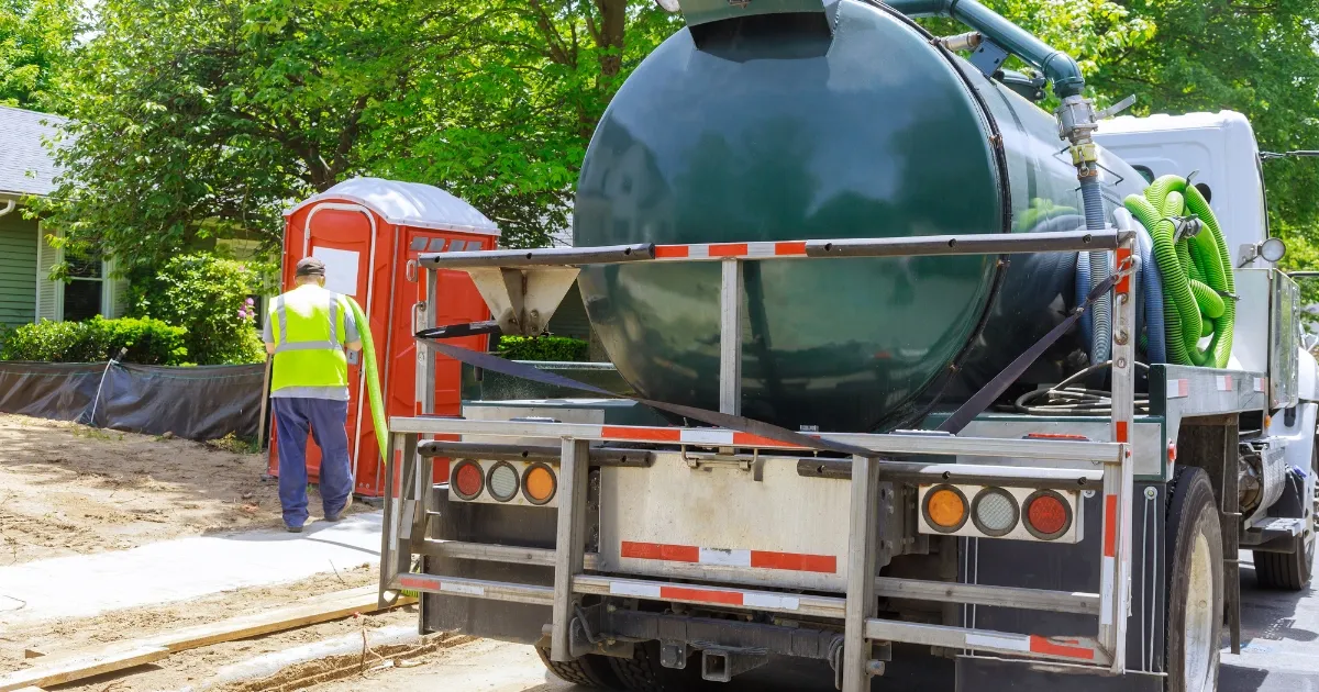 'A technician inspecting and cleaning a septic tank surrounded by nature.' Importance of Proper Septic Tank Maintenance