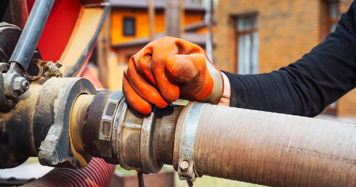 a hand connecting the plumbing pipe into the pumper truck