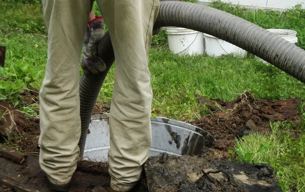 a person using a plumbing tube to clean the septic system