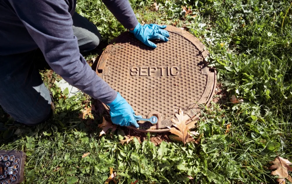 hand with gloves holding the cover of septic tank