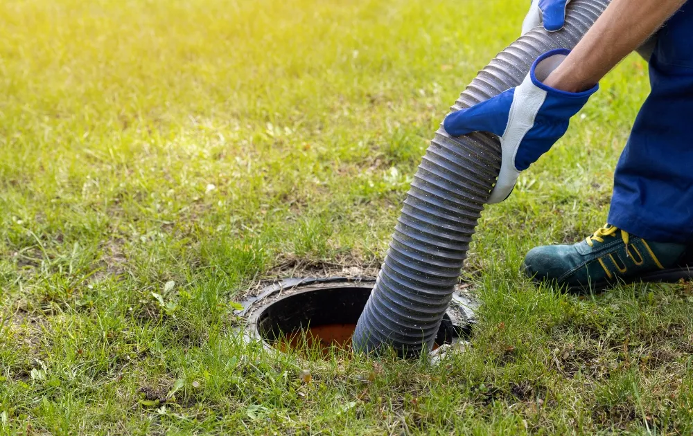 a hand inserting a plumping tube into the septic system