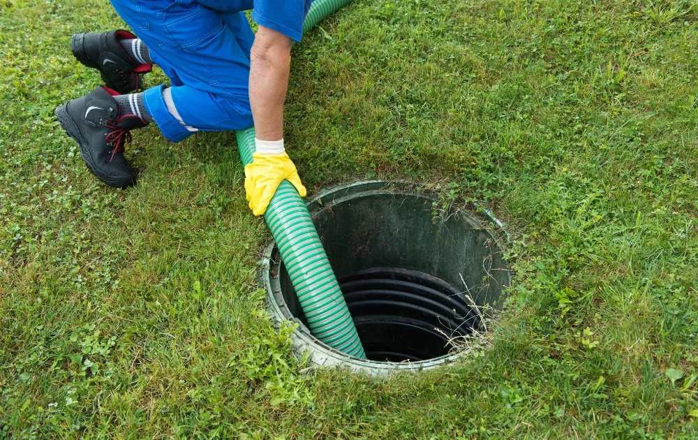 a man inserting a plumbing tube in the septic tank