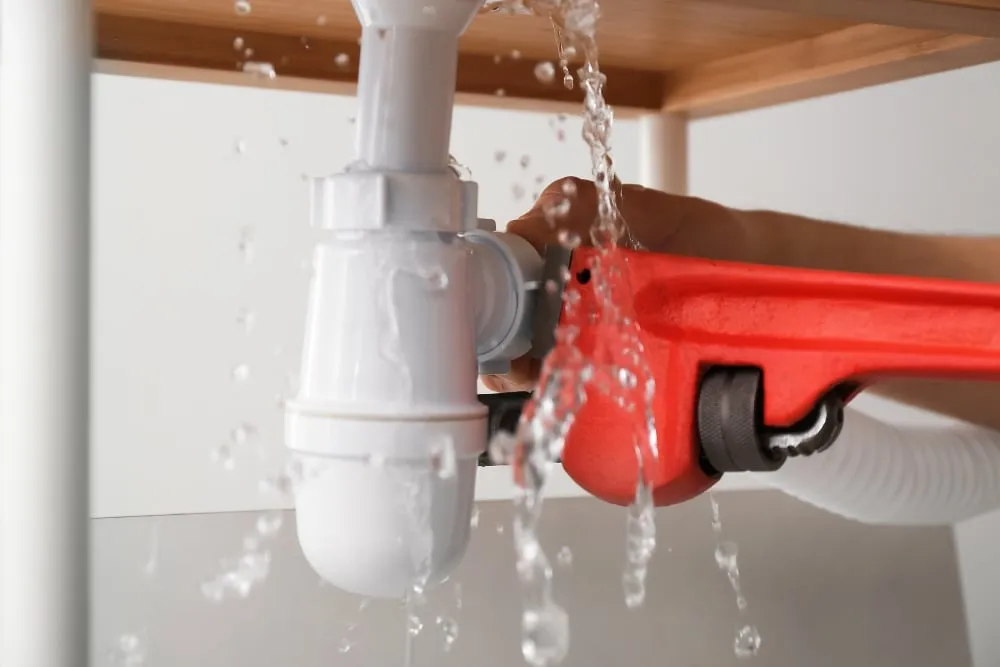 water leaking in the pipe and wrench