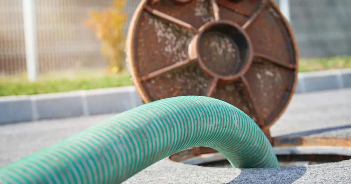 an open septic tank with a green plumbing tube on it