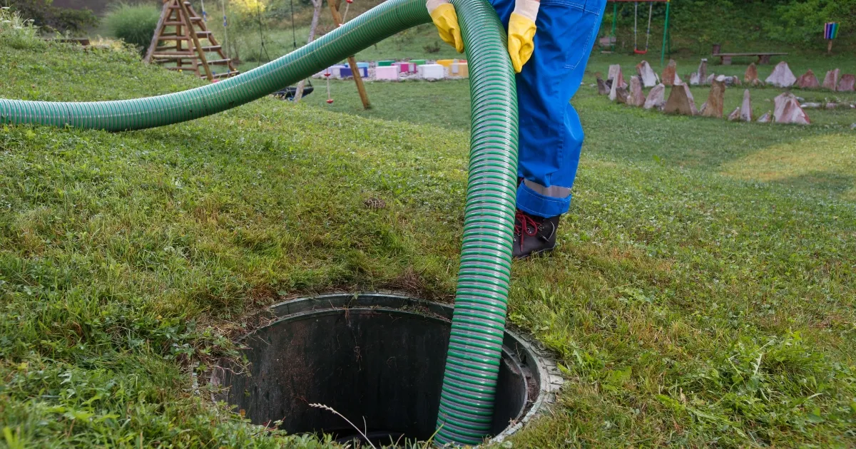 a person with yellow gloves inserting a plumbing tube into the septic tank