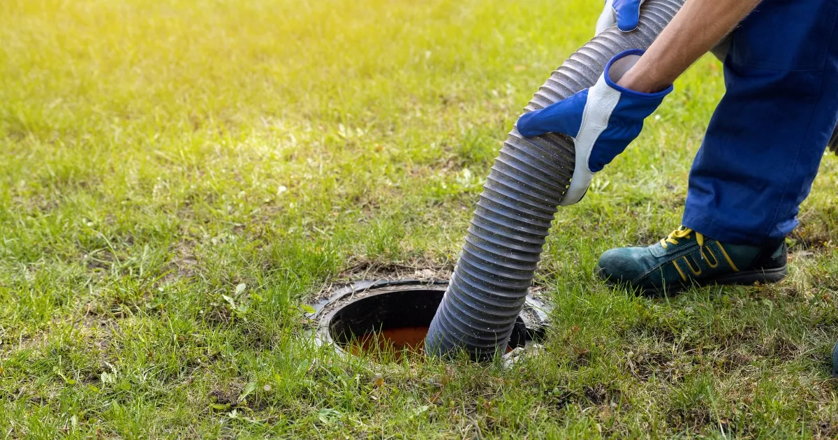 a man inserting a plumbing tube into the septic system