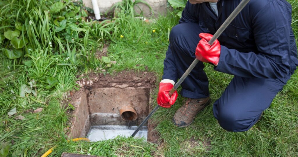 a man holding a metal stick and fixing the blocked drainage